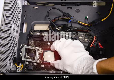 Image of a technician inserting a CPU chip onto a computer motherboard. Stock Photo