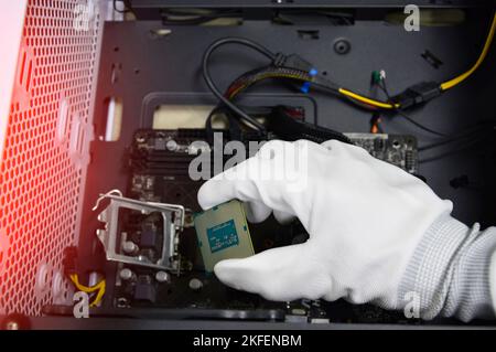 Image of a technician inserting a CPU chip onto a computer motherboard ...