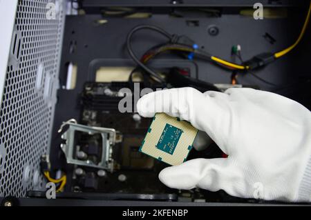 Image of a technician inserting a CPU chip onto a computer motherboard. Stock Photo