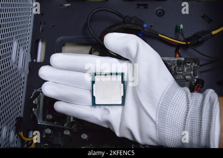 Picture of a hand wearing white gloves with a CPU chip placed on it. Stock Photo