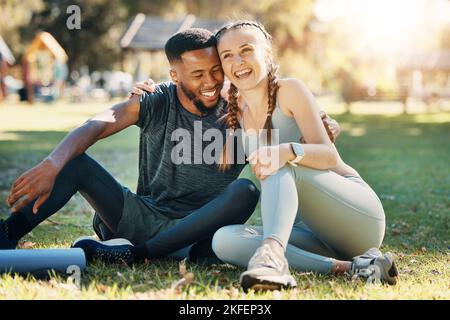 Couple, fitness and sitting on grass, park or lawn together in sunshine for fitness, wellness and health. Interracial relationship diversity or black Stock Photo