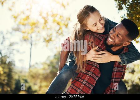 Love, couple and piggy back in nature on vacation, holiday or date outdoors. Romance, diversity and happy man carrying woman on shoulders, having fun Stock Photo
