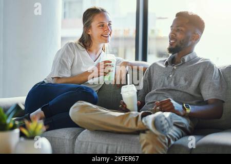Love, healthy and smoothie with a diversity couple on a sofa in the living room of their home to relax together. Weight loss, diet and nutrition with Stock Photo