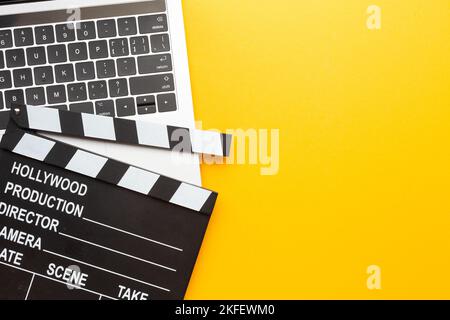 Office stuff with movie clapper, laptop, coffee cup, on yellow table - top view shot. High quality photo Stock Photo