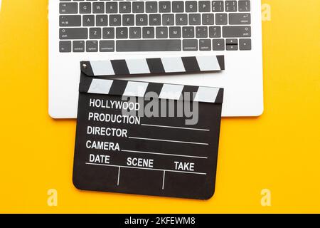 Office stuff with movie clapper, laptop, coffee cup, on yellow table - top view shot. High quality photo Stock Photo