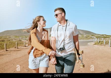 Summer, love and skateboard with a couple walking outdoor in nature together during summer for romance. Holding hands, mountain and nature with a man Stock Photo