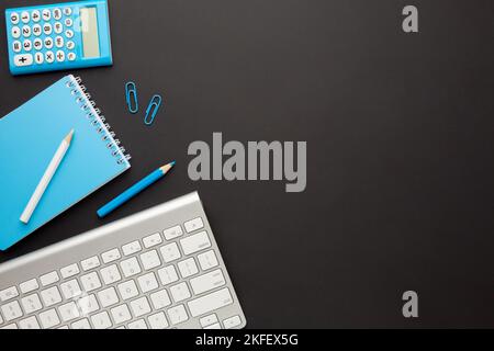 Working black table with a keyboard, calculator, notebook, pencil and paper clips. Space for your inscription. Stock Photo