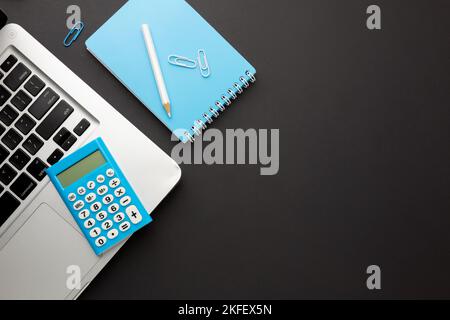 Working black table with laptop, calculator, pencil, notebook and paper clips. Space for your inscription. Stock Photo