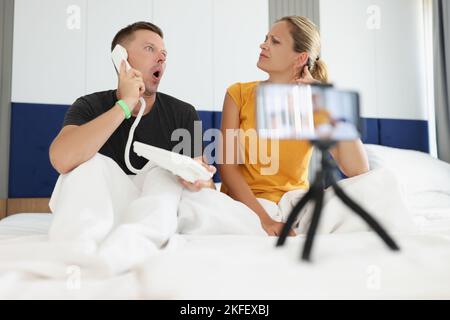Young couple lies in bed and takes selfie on mobile phone. Stock Photo