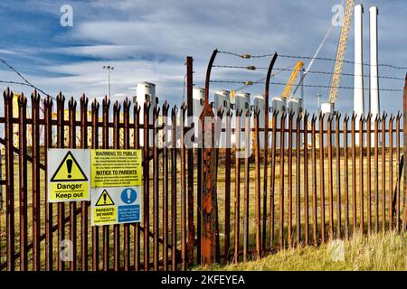 Cromarty Firth Nigg Scotland public and parent danger warning signs on wind turbine construction yard fence Stock Photo