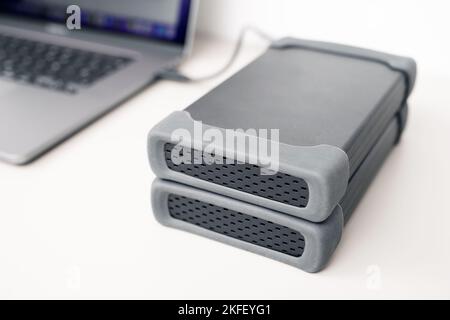 Close up of Two External hard drives storage connected to a modern laptop computer on desk Stock Photo