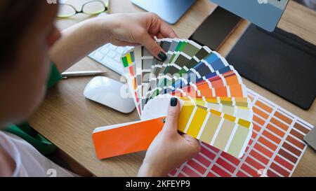 Female designer holding color samples and choosing color samples for projects. Stock Photo