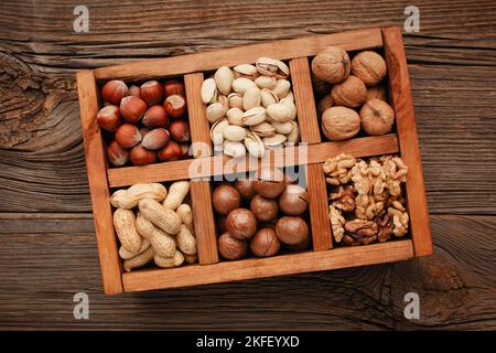 Various nuts selection: peanuts, hazelnuts, chestnuts, walnuts, pistachio and pecans in wooden box. Top view with space for your text Stock Photo