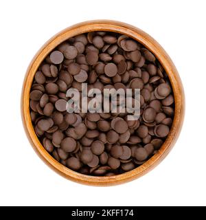 Bittersweet chocolate drops, couverture in a wooden bowl. Chocolate coating mass in drop form. A topping and flavoring for cookies and desserts. Stock Photo
