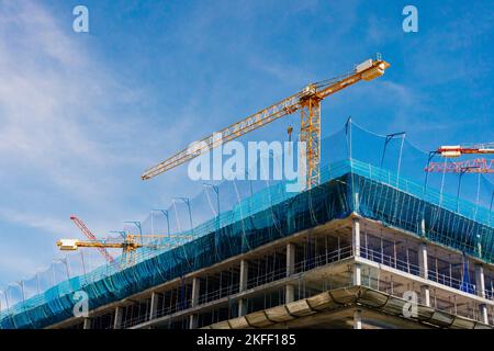 Building construction site with several tower cranes in the blue sky Stock Photo