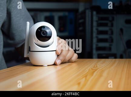 White ip camera lies on wooden floor, man using ip camera Stock Photo
