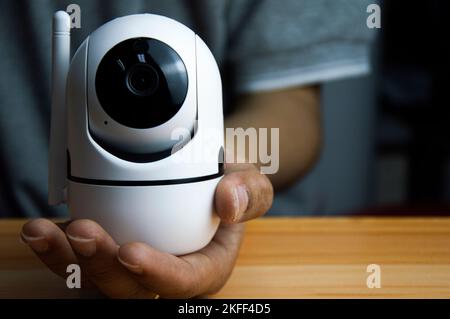 White ip camera lies on wooden floor, man using ip camera Stock Photo