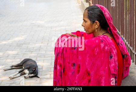 NEW DELHI - SEP 20: Unidentified indian woman sitting on the ground and dressed in traditional bright red dress in New Delhi on September 20. 2022 in Stock Photo