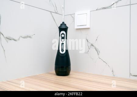 Black portative oral irrigator on wooden table at a bathroom Stock Photo