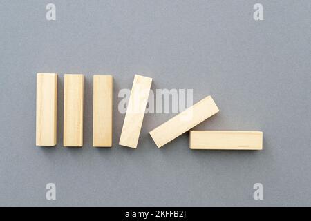 Row of falling vertical wooden shapes business concept picture about team building, leadership, supporting. Blank wooden figures on gray background. Stock Photo