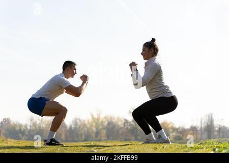 Two amazing and attractive fit friends are doing squad exercise and smiling Stock Photo