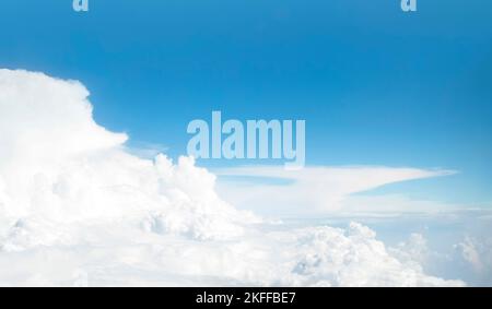 Panoramic view of blue sky and сumulus clouds through an airplane window. Flight above white cloud and horizon. Stock Photo
