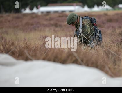 A German Paratrooper derigs his Polish parachute after landing on the Drop Zone during Exrcise Falcon Leap onto Ginkelse Heide Drop Zone, Arnhem, Netherlands., Sep. 14, 2022. More than 1000 Paratroopers from all over the world, 13 different nationalities, multiple airdrops per day, and training with each other equipment for two weeks. this is NATO's largest technical airborne exercise Stock Photo