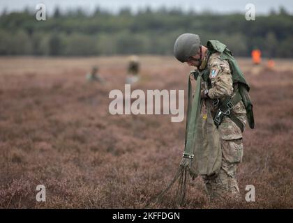 A Dutch Paratrooper packs away his German T-10 parachute after landing on the Drop Zone during Exrcise Falcon Leap onto Ginkelse Heide Drop Zone, Arnhem, Netherlands., Sep. 14, 2022. More than 1000 Paratroopers from all over the world, 13 different nationalities, multiple airdrops per day, and training with each other equipment for two weeks. this is NATO's largest technical airborne exercise Stock Photo