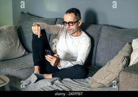 Man on couch with smartphone. Stock Photo