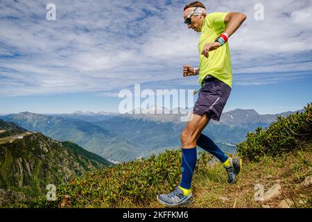 Rosa Khutor, Russia - September 10, 2022: male athlete running down steep mountainside in Rosa Wild Trail Stock Photo