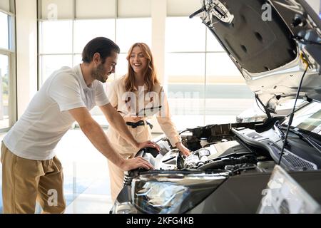Joyful auto dealership client is inspecting new vehicle in showroom Stock Photo