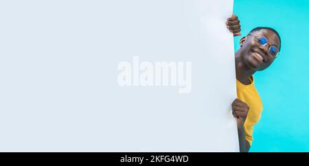 Banner with a black boy coming out from behind a white big board with copy space for text and design Stock Photo