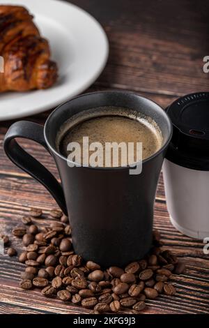 Relaxing americano coffee in black porcelain cup and take away cup on wooden table Stock Photo