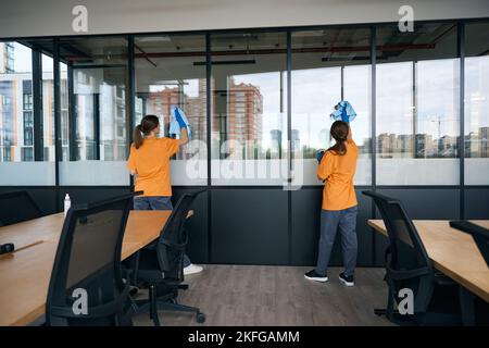 Two women employees cleaning company wash windows in coworking space Stock Photo