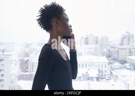 A young black woman using phone and looks away. A young woman with short haircut. Lifestyle photo with copy space. High quality photo Stock Photo