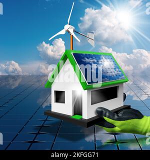 Hand with protective work glove, holding a small model house with solar panels and a small wind turbine on the roof. Renewable energy concept. Stock Photo