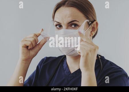 Female doctor putting on surgical face mask and medical goggle Stock Photo