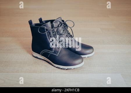 A pair of new black leather boots on the wooden floor. Stock Photo