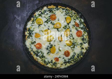 homemade tart pie with spinach, fresh tomatoes and basil leaves Stock Photo