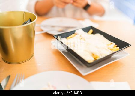 A closeup of raclette with pears in a black plate on the wooden table Stock Photo