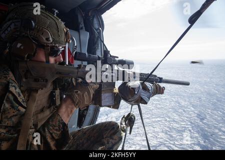 U.S. Marine Corps Sgt. Robert “Bobby” Doerr Jr. a scout sniper with Battalion Landing Team 2/5, 31st Marine Expeditionary Unit, fires a M110 Semi-Automatic Sniper System during an aerial live-fire out of a SH-60 Sea Hawk in the Philippine Sea, Sept. 16, 2022. The scout snipers conducted the live-fire to hone their skills and maintain combat readiness. The 31st MEU is operating aboard ships of the Tripoli Amphibious Ready Group in the 7th Fleet area of operations to enhance interoperability with allies and partners and serve as a ready response force to defend peace and stability in the Indo-Pa Stock Photo