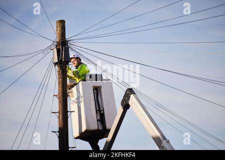 BT openreach engineer working on telephone wires from a cherry picker Stock Photo