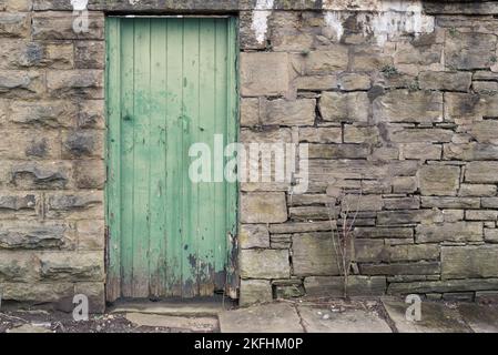 Old green wooden back gate with old stone walls Stock Photo