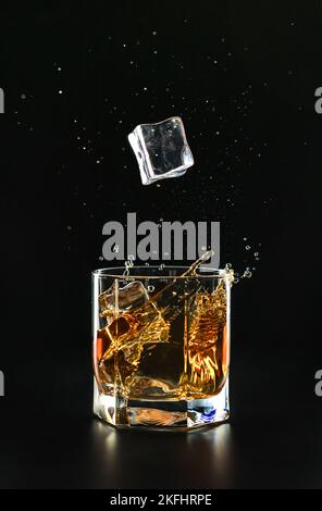 Ice cube falls in a glass with red liquid Stock Photo - Alamy