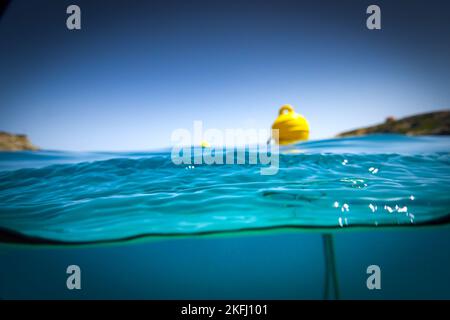Yellow buoy floating on water surface of sea against clear blue sky during sunny day Stock Photo