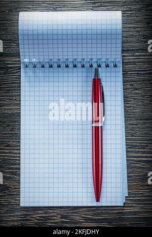 Checked notebook ballpoint pen on vintage wooden board. Stock Photo
