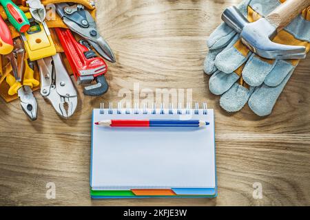 Construction tooling tool belt protective gloves claw hammer notebook pencil. Stock Photo