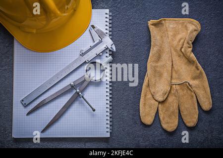 Copybook hard hat divider slide caliper safety gloves construction concept. Stock Photo