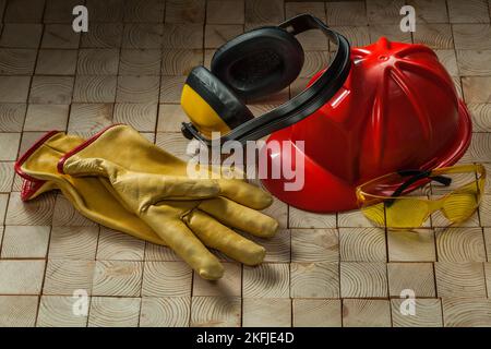 construction safety tools leather gloves red helmet ggogles and earphones on wooden background Stock Photo