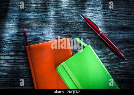 Green and orange notebooks on wooden board. Stock Photo